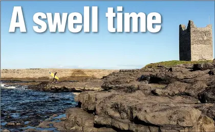  ?? The New York Times/THERESE AHERNE ?? A surfer walks along the shore near the two surf breaks at the mouth of the Easkey River, which flows into the Atlantic Ocean next to a ruin called Roslee Castle in Easkey, Ireland.