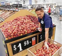  ??  ?? Produce stocker Ronel Ybarola arranges peaches in Katy’s newest Walmart. The retailer has 100 locations in the Houston area.