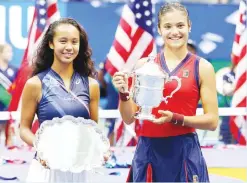  ??  ?? LEYLAH ANNIE FERNANDEZ of Canada (left) holds the runnerup trophy as Emma Raducanu of Great Britain celebrates with the championsh­ip trophy after their US Open women's singles final match at the Billie Jean King National Tennis Center on Sept. 11 in New York City. (AFP)