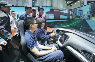  ?? WANG ZHUANGFEI / CHINA DAILY ?? Visitors test a driving simulator during last year’s Beijing auto show. With steady economic growth, experts say there is likely to be a sustained demand for automobile­s in the years to come.