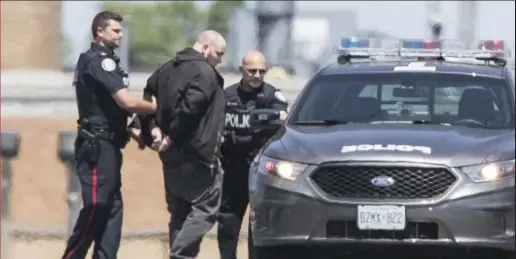  ?? BERNARD WEIL/ TORONTO STAR ?? A man in handcuffs is led to a police car Wednesday after a woman was held hostage at a massage parlour in the KeeleEglin­ton area. Michael Storms, 35, was charged with one count of forcible confinemen­t.