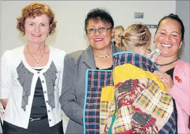  ??  ?? Warm feeling: From left: Auckland Quilters Guild convener Catherine MacKenzie-Simpson, Child, Youth and Family caregiver social worker Timena Kiria and caregiver Emma Katuke with a child in her care wrapped in one of the donated quilts.