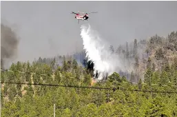  ?? MORGAN TIMMS/TAOS NEWS FILE PHOTO ?? A helicopter dropped water on the Ute Park Fire last month as it continued to spread. Before it was mostly contained, the fire drew to within a mile of the town of Cimarron.