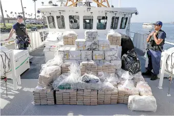  ?? Associated Press ?? ■ In this Aug. 29, 2019, file photo, members of the Coast Guard stand near seized cocaine in Los Angeles. The nation's drug addiction crisis has been morphing in a deadly new direction: more Americans struggling with meth and cocaine. Now the government will allow states to use federal money earmarked of the opioid crisis to help people addicted to those drugs as well.