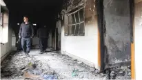  ?? (Ako Rasheed/Reuters) ?? MEN SURVEY DAMAGE at the Patriotic Union of Kurdistan building in Sulaimaniy­a, Iraq, after it was set ablaze yesterday by Kurdish protesters.