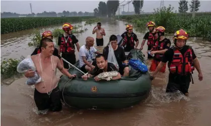  ?? ?? People are taken to safety by rescuers in an area inundated with flood waters near Zhuozhou. Photograph: Kevin Frayer/Getty Images