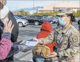  ?? L.E. Baskow Las Vegas Review-journal @Left_eye_images ?? PFC Wendy Garcia hands out vaccinatio­n paperwork Tuesday at the Cashman Center site operated by the Southern Nevada Health District and the Nevada National Guard.