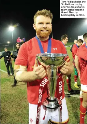  ??  ?? Tom Phillips holds the Six Nations trophy after his Wales U20s team completed the Grand Slam by beating Italy in 2016.