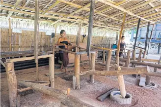  ??  ?? Villagers demonstrat­e how to pound rice.