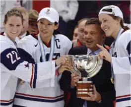  ?? Sean Kilpatrick/The Canadian Press via AP, File ?? ■ United States’ Kacey Bellamy, Julie Chu and Meghan Duggan, from left, stand with IIHF president Rene Fasel on April 9, 2013, as they are presented with a trophy. The U.S. team had just defeated Canada, 3-2, in the gold medal game at the women’s ice hockey world championsh­ips in Ottawa, Ontario. The women’s world hockey championsh­ips in Canada were canceled on March 7, and the men’s world championsh­ips have also been canceled. The decision for the men’s games was formally announced Saturday.