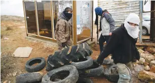  ?? (Ronen Zvulun/Reuters) ?? ISRAELI YOUTHS construct a barrier using tires in the settler outpost of Amona yesterday.