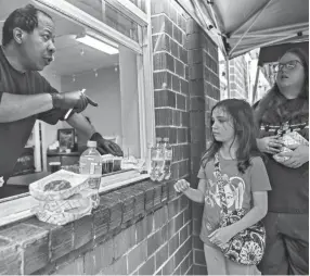  ?? PHOTOS BY ARIEL COBBERT/THE COMMERCIAL APPEAL ?? Volunteer Brad Watkins hands out grab-and-go meals through a window at Caritas Community Center and Cafe in Binghampto­n last Tuesday. Caritas Community Center and Cafe offers free daily meals to out-of-work Memphians.