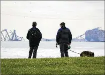  ?? ULYSSES MUÑOZ/THE BALTIMORE BANNER VIA AP ?? Two men observe the Francis Scott Key Bridge wreckage from Fort McHenry, Maryland, on Tuesday. The bridge collapsed when a cargo ship crashed into it.