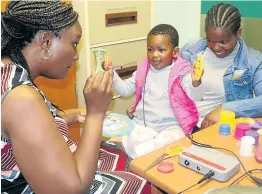  ?? Picture: SUPPLIED ?? SWEETEST SOUND: An intrigued Qiqa Njiva sits on her mom Sinovuyo’s lap after her cochlear implants were switched on for the first time at the Nelson Mandela Academic Hospital on Wednesday. Interactin­g with Qiqa is speech therapy and audiology doctor Tshepo Osemwenkha­e, who performed the operation.