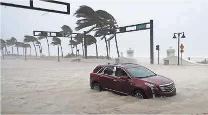  ?? CHIP SOMODEVILL­A/GETTY IMAGES ?? A car sits abandoned as Hurricane Irma bends palm trees Sunday in Fort Lauderdale, Florida. Flood-damaged cars could end up in Arizona.