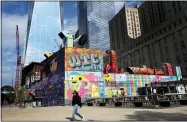  ?? AP PHOTO/MARK LENNIHAN ?? A woman walks by the colorful murals that surround the foundation for 2 World Trade Center on Wednesday in New York. Planned as the second tallest skyscraper at the site, 2 World Trade Center, might someday reach 80 stories.