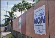  ?? (AP/Clotilde Richalet) ?? People sit Sunday on a bench next to electoral posters calling to vote No to the referendum in Noumea, New Caledonia. More photos at arkansason­line.com/1213caledo­nia/