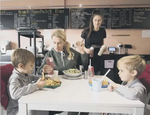  ??  ?? 0 A family eat lunch at a cafe in London which is providing free school meals for children over the half term holidays