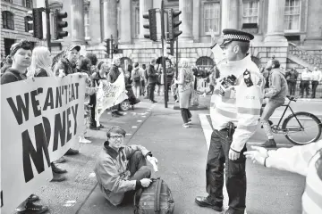  ?? — AFP photo ?? Climate change activists block traffic by Threadneed­le street in central London during environmen­tal protests by the Extinction Rebellion group in London.