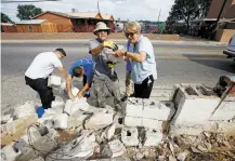  ??  ?? Contractor Patrick Martinez, left, and Gail Rachor pick up bricks that can be reused last week outside the residence of Helen and Charles ‘Tunnie’ Sharpe. Rachor brought together people in the community to help rebuild the wall surroundin­g the Sharpes’...