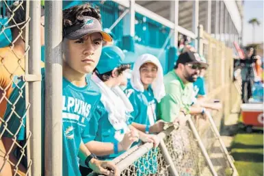  ?? YUTAO CHEN/STAFF PHOTOGRAPH­ER ?? Miami Dolphins fan Cameron Careallo, 14, watches players train during the team’s first day of summer training camp at the Baptist Health Training Facility at Nova Southeaste­rn University in Davie on Thursday. The training camp is expected to move by...