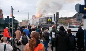  ?? Marie Odgaard/EPA ?? People look on as the fire burns at the old stock exchange in Copenhagen. Photograph: Ida