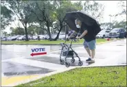  ?? LYNNE SLADKY — THE ASSOCIATED PRESS ?? Franklin Castellon, 76, shields himself from the rain as he walks to an early voting site, on Monday, Oct. 19.