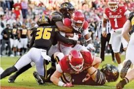  ?? AP PHOTO/MICHAEL WOODS ?? Arkansas running back Raheim Sanders, at center with ball, pushes past Missouri’s DJ Jackson (36) and Chad Bailey to score a touchdown during the first half of Friday’s matchup of SEC border rivals in Fayettevil­le, Ark.