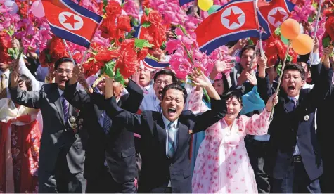  ?? AFP ?? Participan­ts wave flowers as they march past a balcony from where North Korea’s leader Kim Jong-un was watching, during a mass rally on Kim Il-Sung square in Pyongyang yesterday.