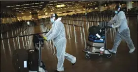  ?? ASSOCIATED PRESS ?? In this July 29 file photo, passengers wearing full protective gear against the spread of Coronaviru­s push their luggage in the departure hall of Zaventem internatio­nal airport in Brussels.