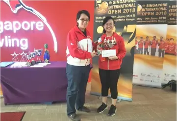  ??  ?? Nur Aina receives her prizes from Singapore Bowling Federation vice president Dr Valerie Teo.