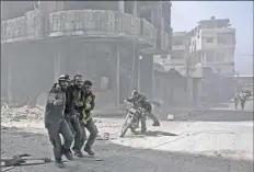  ?? Abdulmonam Essa/AFP/Getty Images ?? Volunteers from the Syrian Civil Defense help a man Tuesday during Syrian government shelling on rebel-held areas of Eastern Ghouta on the outskirts of Damascus.