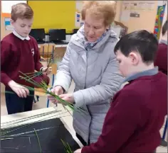  ??  ?? Una Casey helps 5th Class pupils from Scoil Phádraig Naofa, Kilcurry make St Brigid’s Crosses.