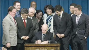  ?? Rich Pedroncell­i Associated Press ?? GOV. JERRY BROWN signs a bill that will automatica­lly enroll millions of private-sector workers in the new California Secure Choice Retirement Savings Program as lawmakers and supporters look on Thursday.