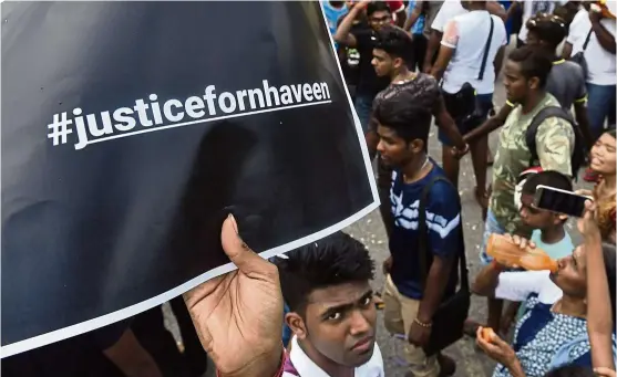  ?? — Photo: GARY CHEN/ The Star ?? T. Nhaveen’s friend with the poster ‘Justice for Nhaveen’ at Nhaveen’s funeral at Batu Gantong Funeral Parlour, Penang.