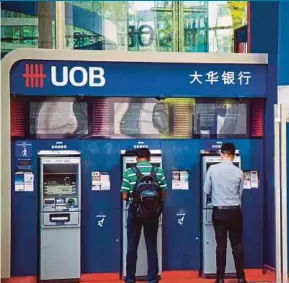  ?? BLOOMBERG PIC ?? Customers at a United Overseas Bank branch in Singapore. The Monetary Authority of Singapore has notified local banks of the delay to the so-called ‘fundamenta­l review of the trading book’.