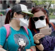  ?? AP ?? Women wear masks as a precaution against the Mers as they watch a smartphone in Seoul on Friday. —