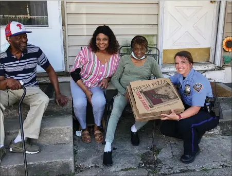  ?? PHOTO COURTESY OF POTTSTOWN POLICE ?? Pottstown Police officer Melinda Beary, right, shares some of her pizza with residents Wednesday. Police had so much pizza delivered on the same day, they decided to share it with community members.