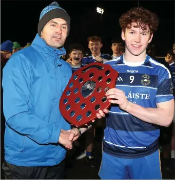  ??  ?? Jeff Branigan presents the Lennon Shield to the winning Coláiste Rís captain Patrick Murtagh.