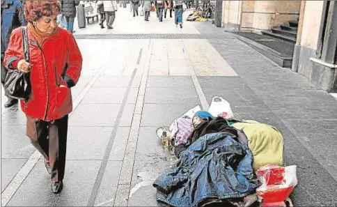  ?? Ignacio Gil ?? Una mujer observa a otra, que duerme en el suelo, en la Gran Via de Madrid