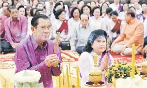  ?? — Gambar AFP ?? TUNAI KEWAJIPAN: Hun Sen (kiri) dan isteri beliau Bun Rany ketika bersembahy­ang di Angkor Wat di wilayah Siem Reap kelmarin.