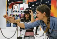  ?? James Nielsen / Houston Chronicle ?? Lingzi Yang demonstrat­es Microsoft HoloLens with help from Marjolijn Beckers at the Grace Hopper Celebratio­n of Women in Computing conference.