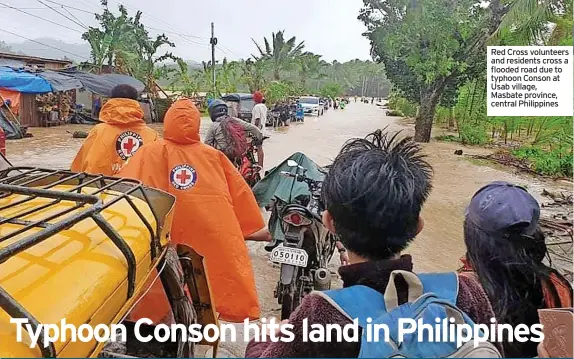  ??  ?? Red Cross volunteers and residents cross a flooded road due to typhoon Conson at Usab village, Masbate province, central Philippine­s