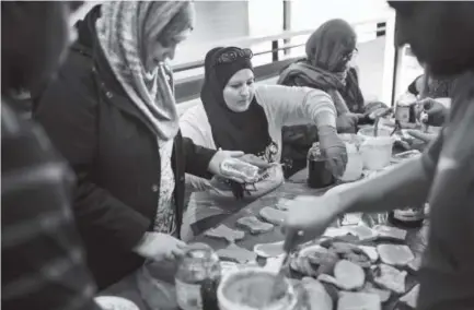  ?? Photos by Justin Edmonds, Special to The Denver Post ?? Farah Afzal, second from left, Sara Westbrook, center, and other local Muslims gather at the University of Colorado Denver to make PB&amp;J sandwiches on Saturday for sack lunches for the homeless.