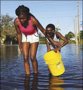  ?? AP PHOTO ?? Nineve Desronvil, 20, left, and her brother Jeffrey 8, wade through their flooded street trying to catch fish in the aftermath of Hurricane Irma in Fort Myers, Fla., yesterday.