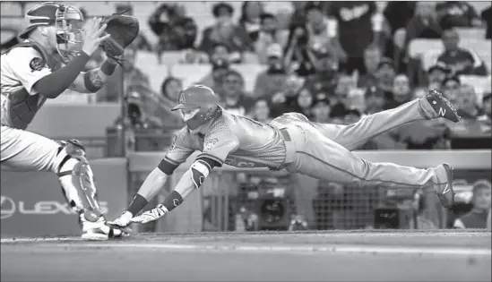  ?? Photograph­s by Wally Skalij Los Angeles Times ?? CATCHER YASMANI GRANDAL is still waiting for the ball as Arizona’s Nick Ahmed dives into home to complete an inside-the-park home run in the first inning.