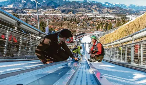  ?? Foto: Ralf Lienert ?? Helfer pflegen die Anlaufspur der Schattenbe­rgschanze. Trotz der frühlingsh­aften Temperatur­en in Oberstdorf erwarten die Organisato­ren keine Probleme an den Wettkampf‰ stätten. Das gilt sowohl für das Springen als auch für den Langlauf.