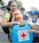  ?? ARIANA CUBILLOS/AP ?? A woman receives an empty container for water during the Red Cross’ first aid shipment in Caracas, Venezuela, on Tuesday.