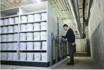  ?? ?? Pathologis­t Martin Wirenfeldt Nielsen moves shelves with buckets in which human brains are stored, in the basement of the University of Southern Denmark.
