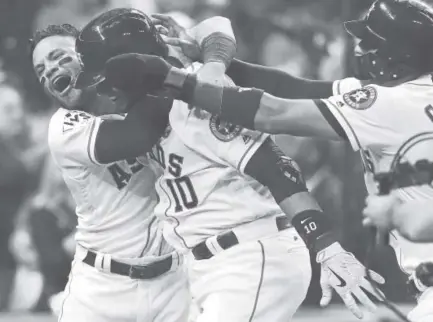  ?? David J. Phillip, The Associated Press ?? Astros first baseman Yuli Gurriel is mobbed by Jose Altuve, left, and Carlos Correa after Gurriel hit a three-run homer against the Dodgers during the fourth inning of Game 5 of the World Series in Houston on Sunday.